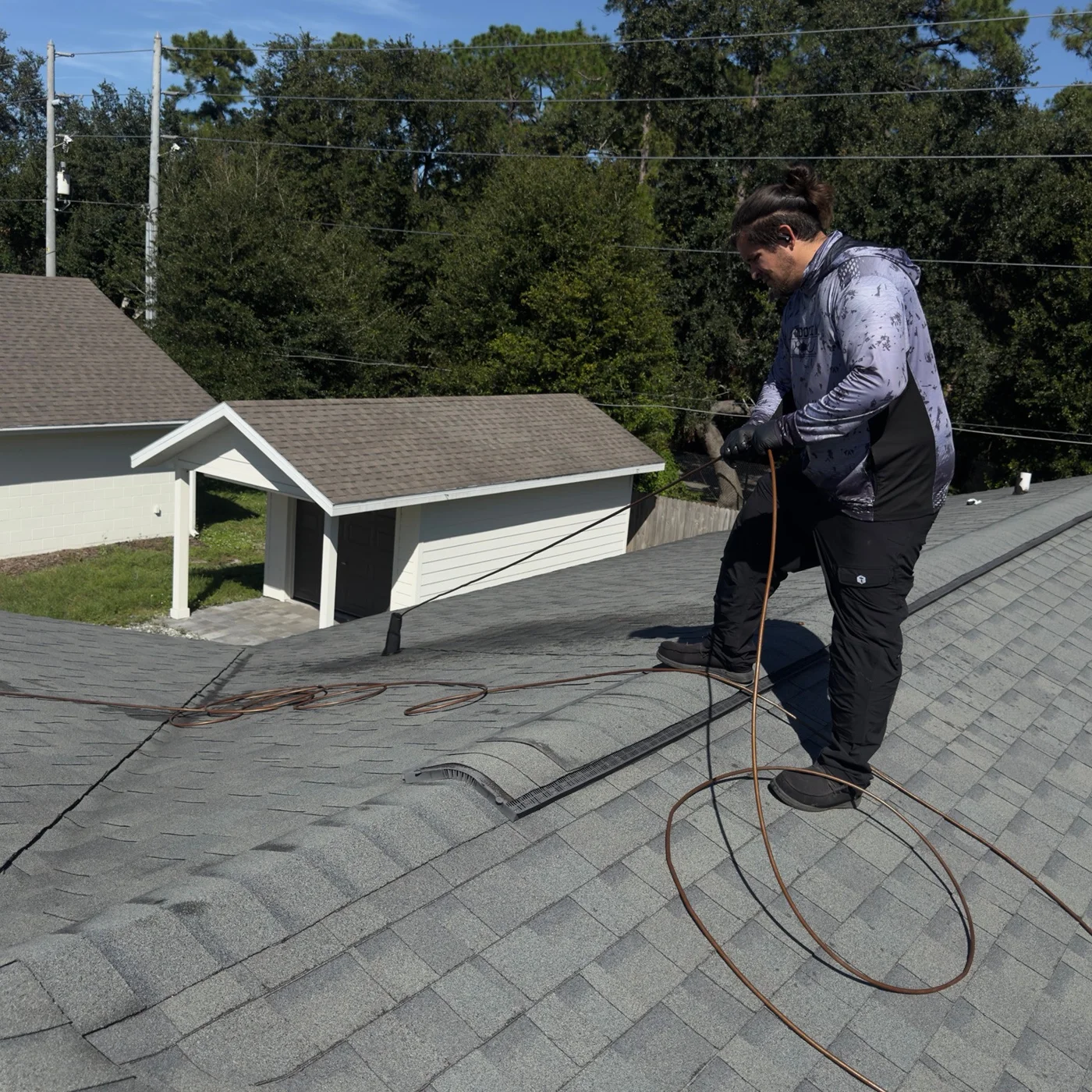 Technician working with a hose beside a roof vent