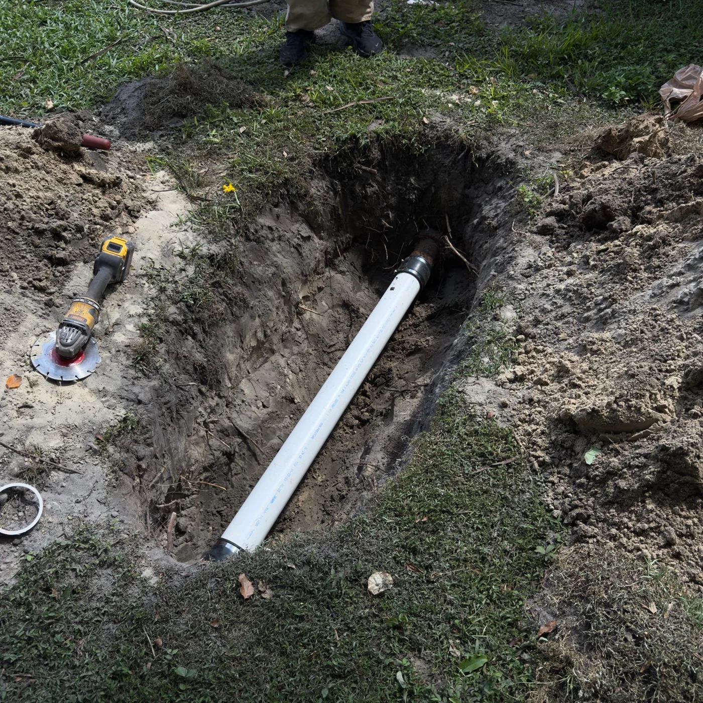 White pipe section and couplings exposed in an excavated trench